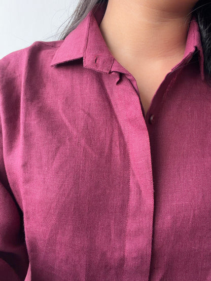A close-up of a person wearing a textured, 3/4th sleeve button-down shirt in berry color.