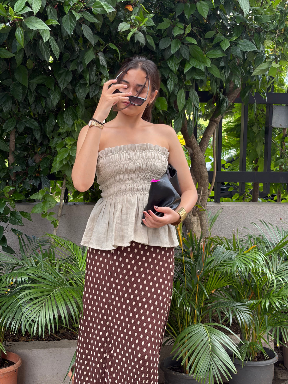 Woman wearing the Lucy beige smocked strapless peplum top with a brown polka-dot midi skirt